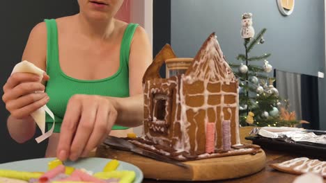 woman decorating a gingerbread house