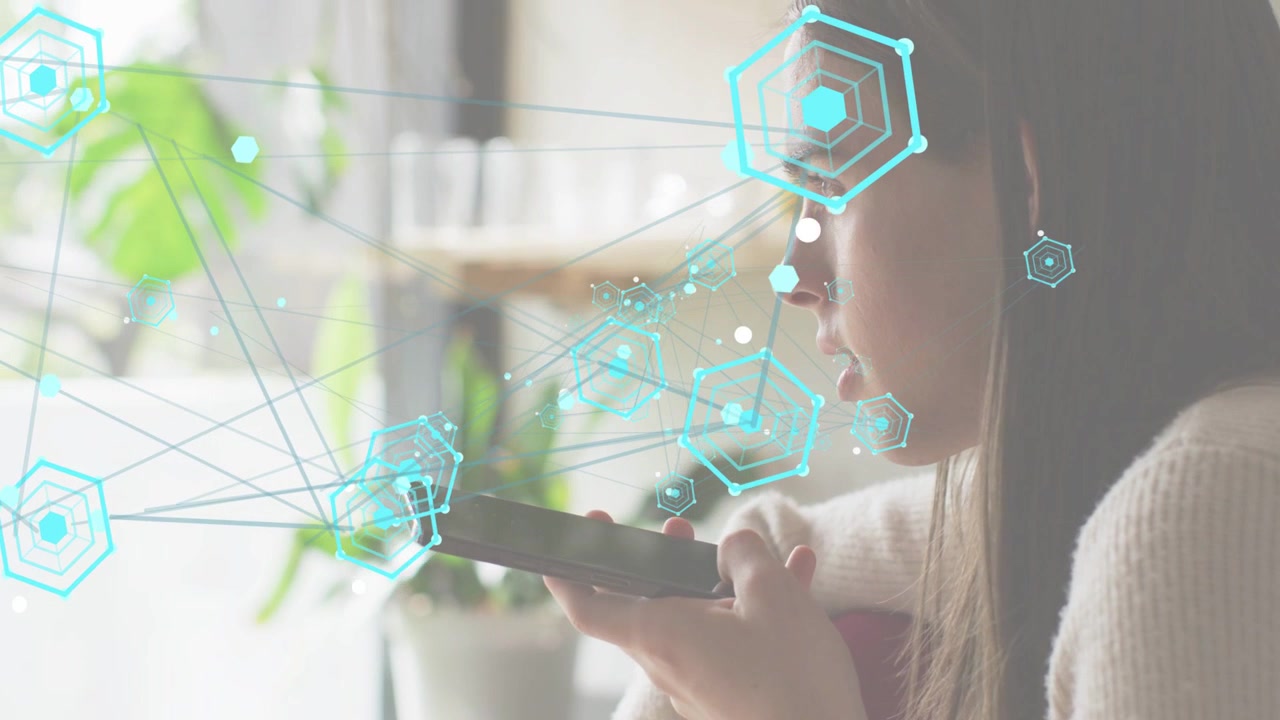Woman sitting near large window speaking into smartphone and activating cyan hexagon tech growing