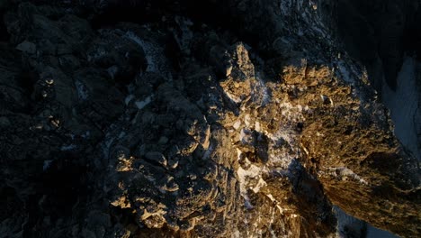 aerial top down shot of showing lighting peak of rocky mountains and steep scrap