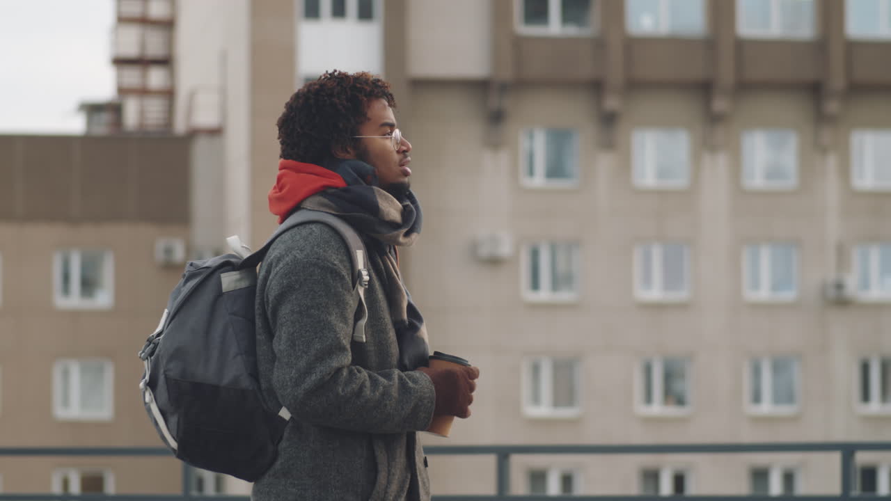 Man Walking in City with Coffee and Backpack