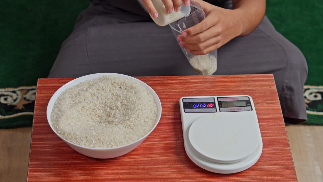 Close-up of person weighing rice on kitchen scale for Zakat al-Fitr