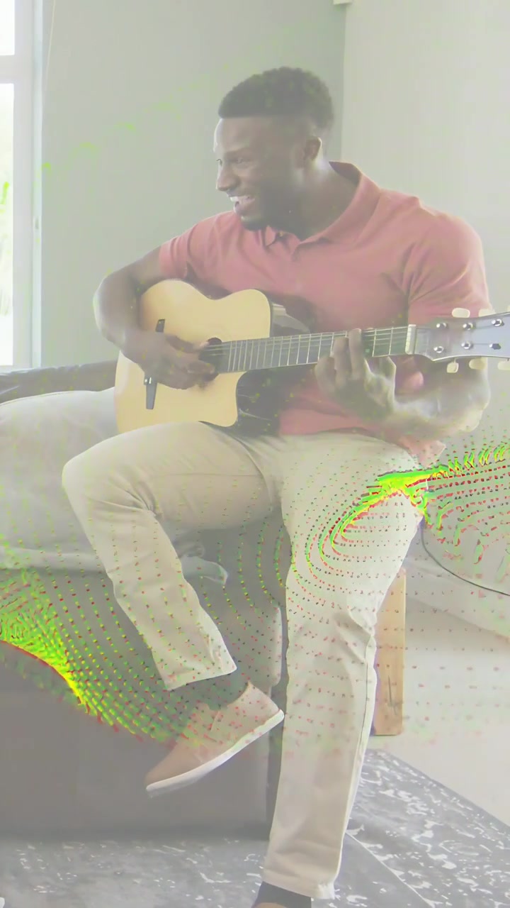 Vídeo vertical: Homem olhando para a esquerda sorrindo, tocando violão acústico em um banquinho enquanto pratica música.