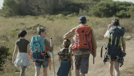 vista posterior de la familia caucásica con mochilas caminando juntos