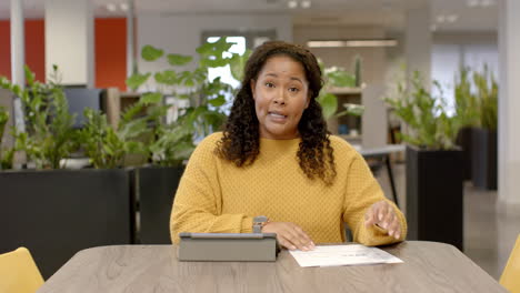 Retrato-De-Una-Mujer-De-Negocios-Birracial-Informal-En-Videollamada-En-La-Oficina,-Cámara-Lenta-Con-Espacio-Para-Copiar