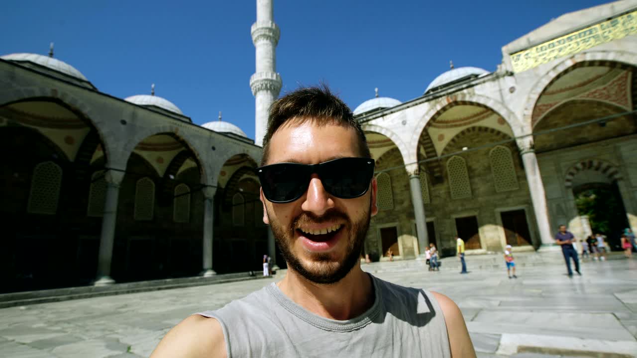 Toma a mano de un hombre turista feliz haciendo una videollamada con la cámara de su smartphone cerca de la famosa Mezquita Azul en Estambul.