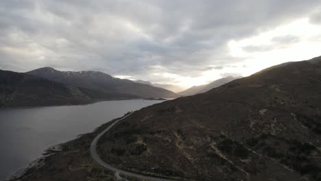 tomada aérea de un avión no tripulado de un camino vacío a través de las montañas en escocia