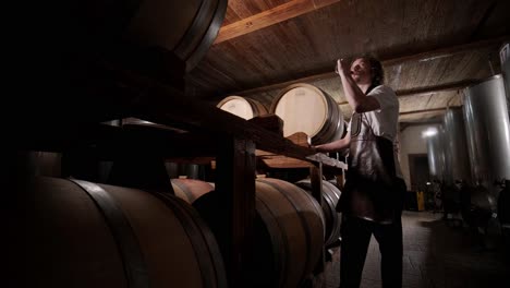 authentic shot of successful male sommelier is tasting a flavor and checking white wine quality poured in transparent glass in a wine cellar.