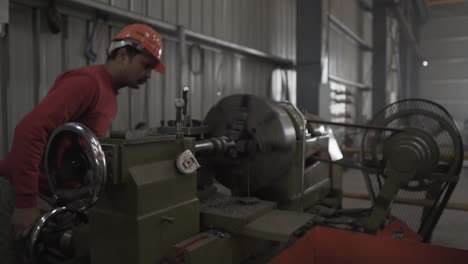 indian factory worker is programming a cnc machine, technician wearing helmet working in mechanical manufactory production line in asia