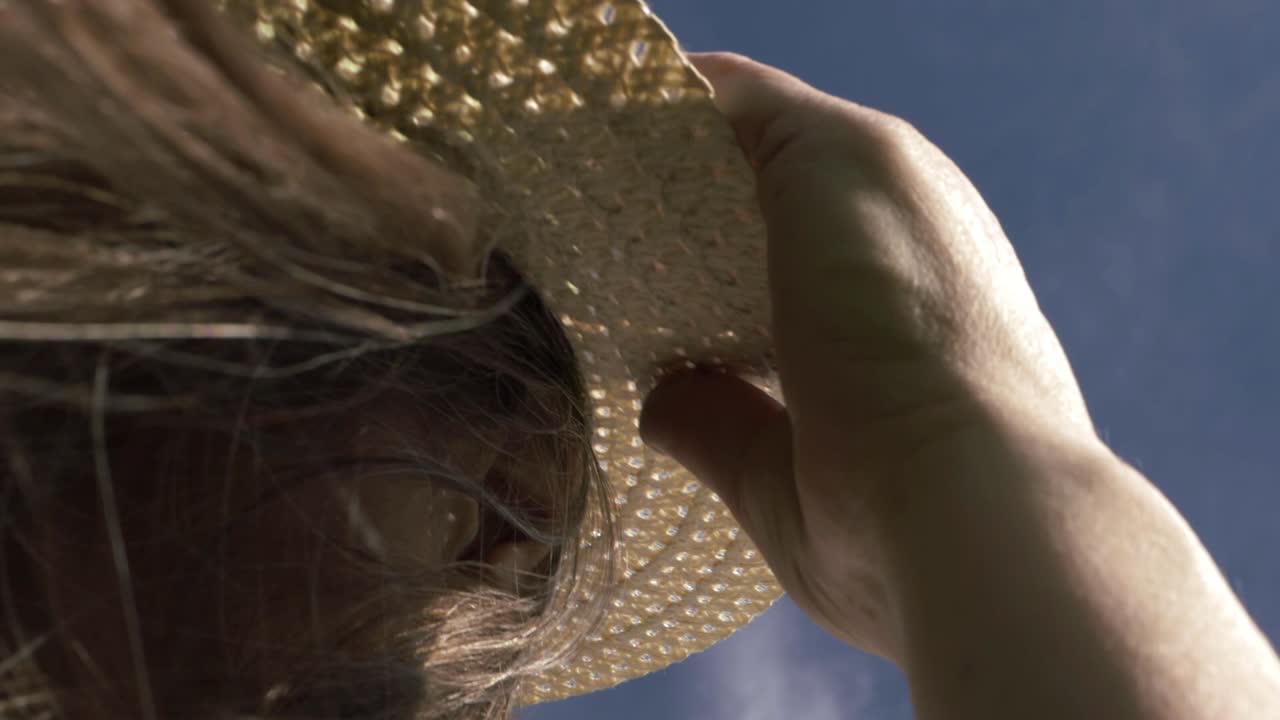 Woman wearing straw hat on windy day close up shot