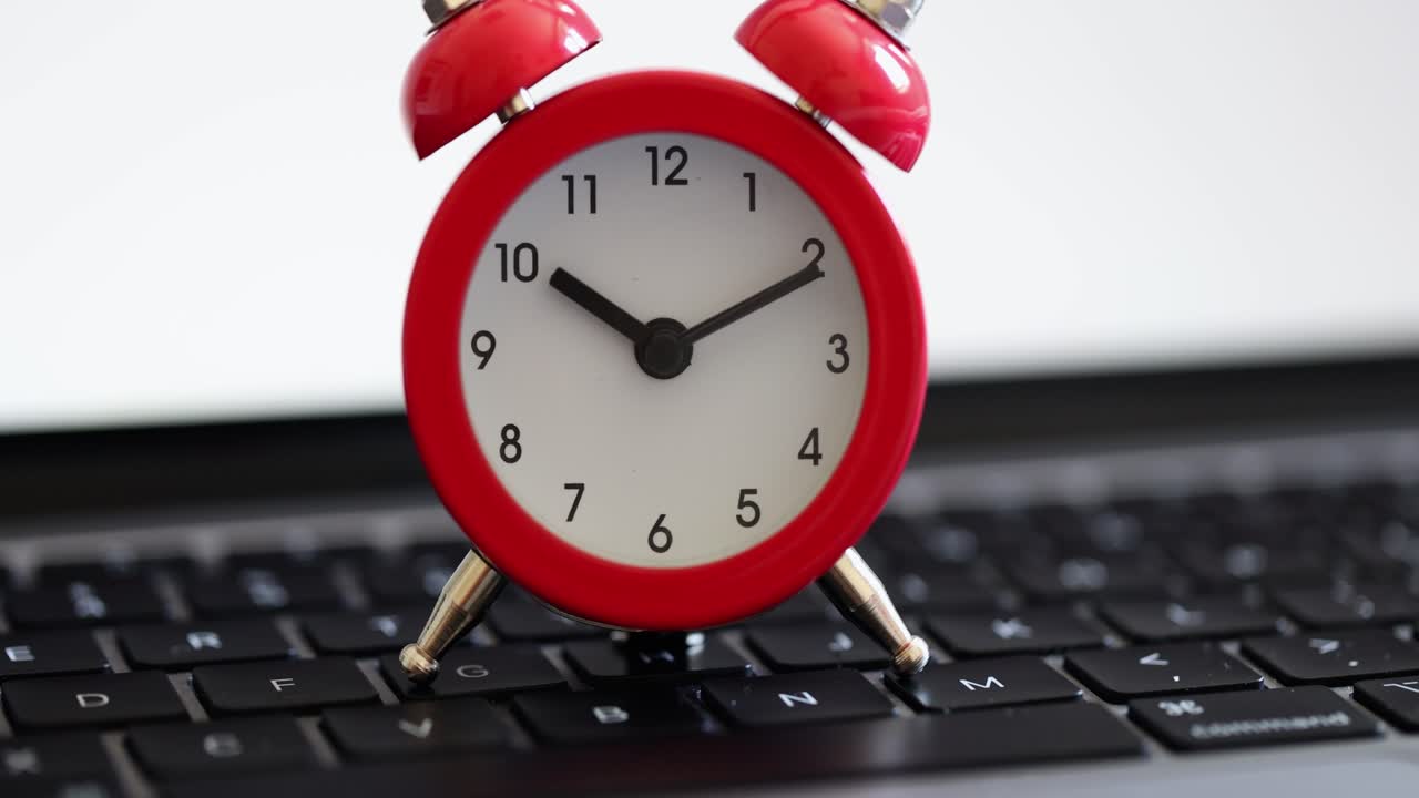 Red alarm clock on a laptop keyboard
