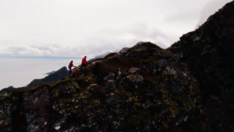 Vista-Aérea-De-Una-Pareja-De-Excursionistas-Y-Su-Perro-Golden-Retriever-En-El-Sendero-Reinbringen-Con-Vistas-A-Gylttinden,-Reine,-Islas-Lofoten,-Noruega