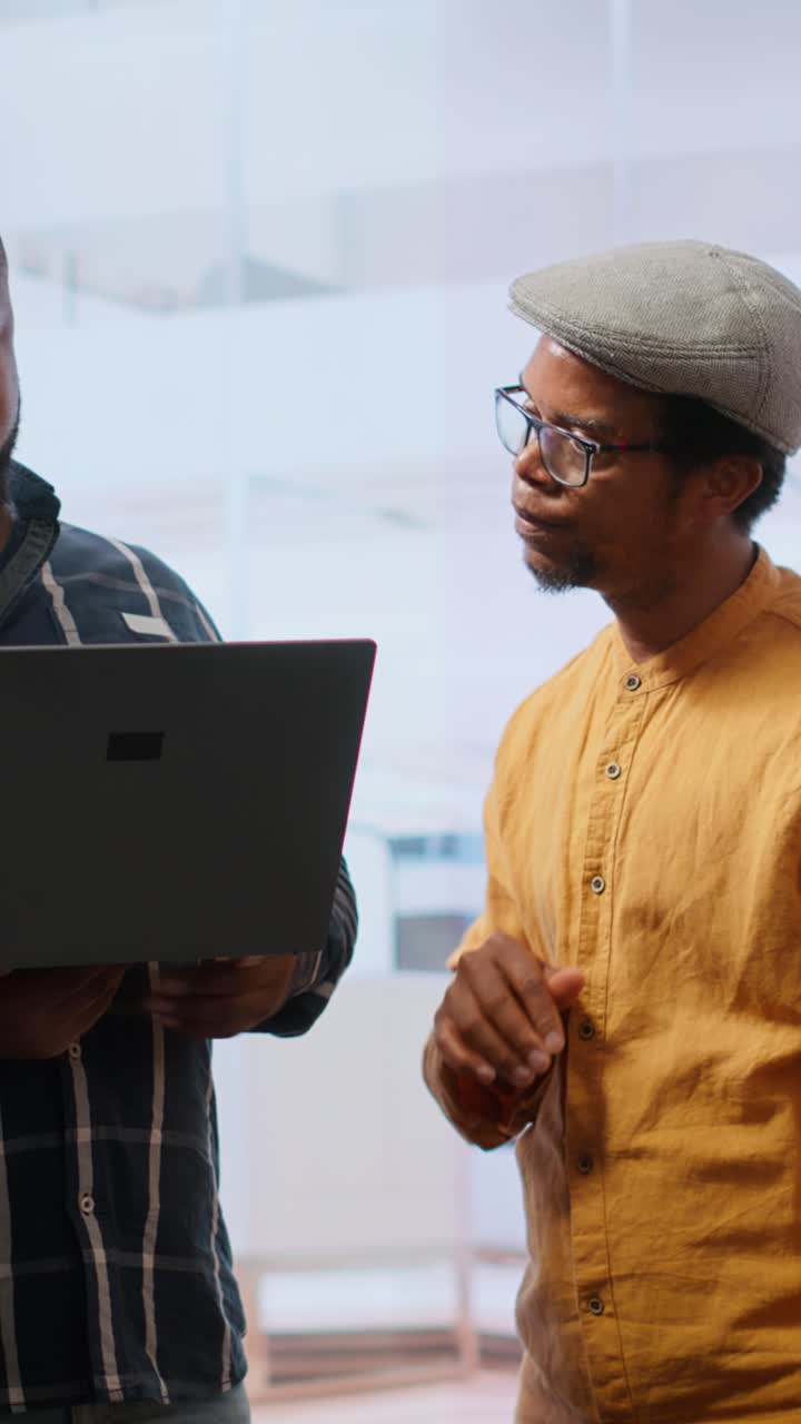 Two Men Discussing Business Strategy Using Laptop in Office