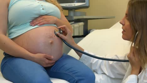 doctor using a stethoscope on a pregnant womans stomach