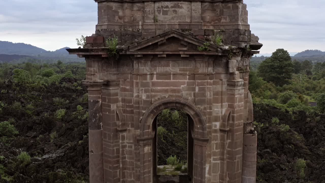 Camera lowers smoothly, moving closer to the ruins of San Juan Parangaricutiro Church