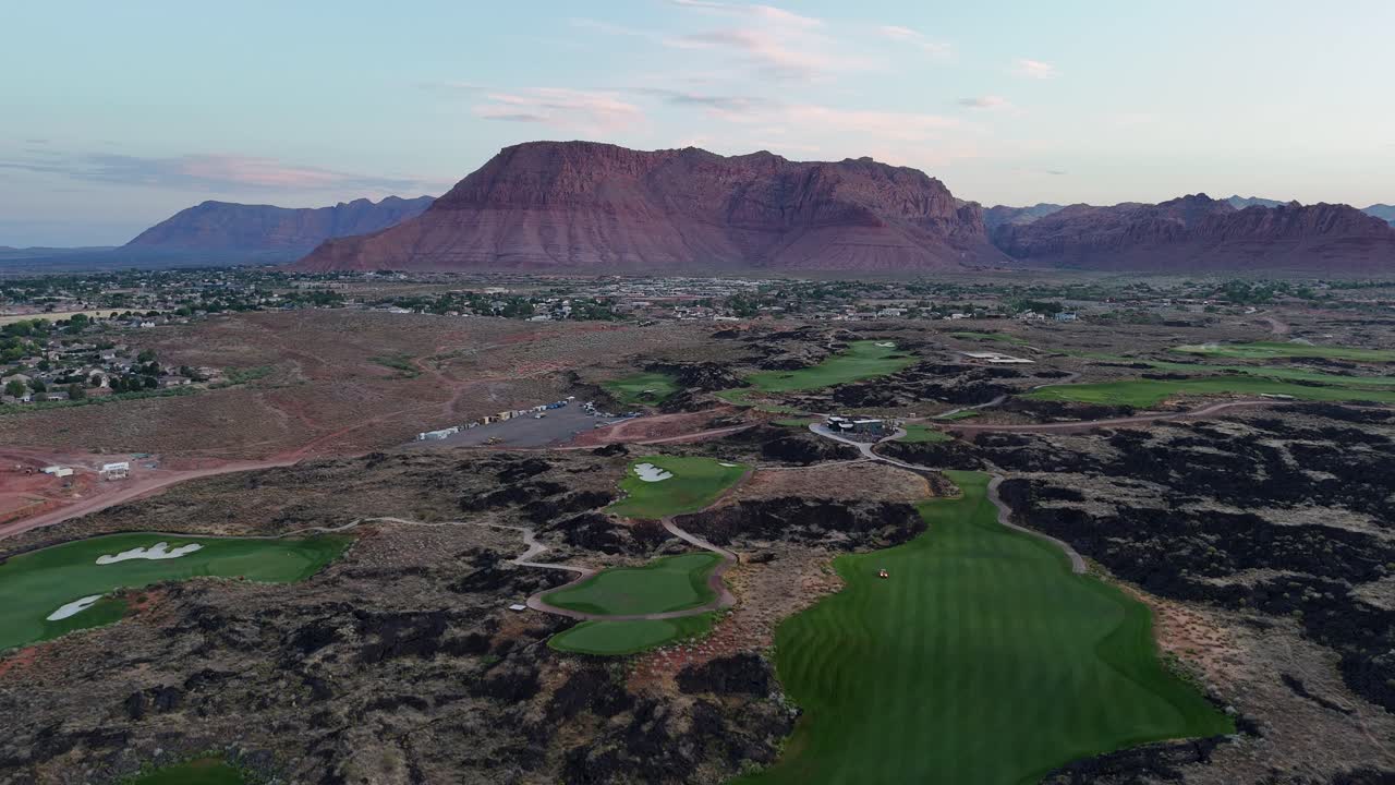 Aerial view of a desert golf course with large red mountains