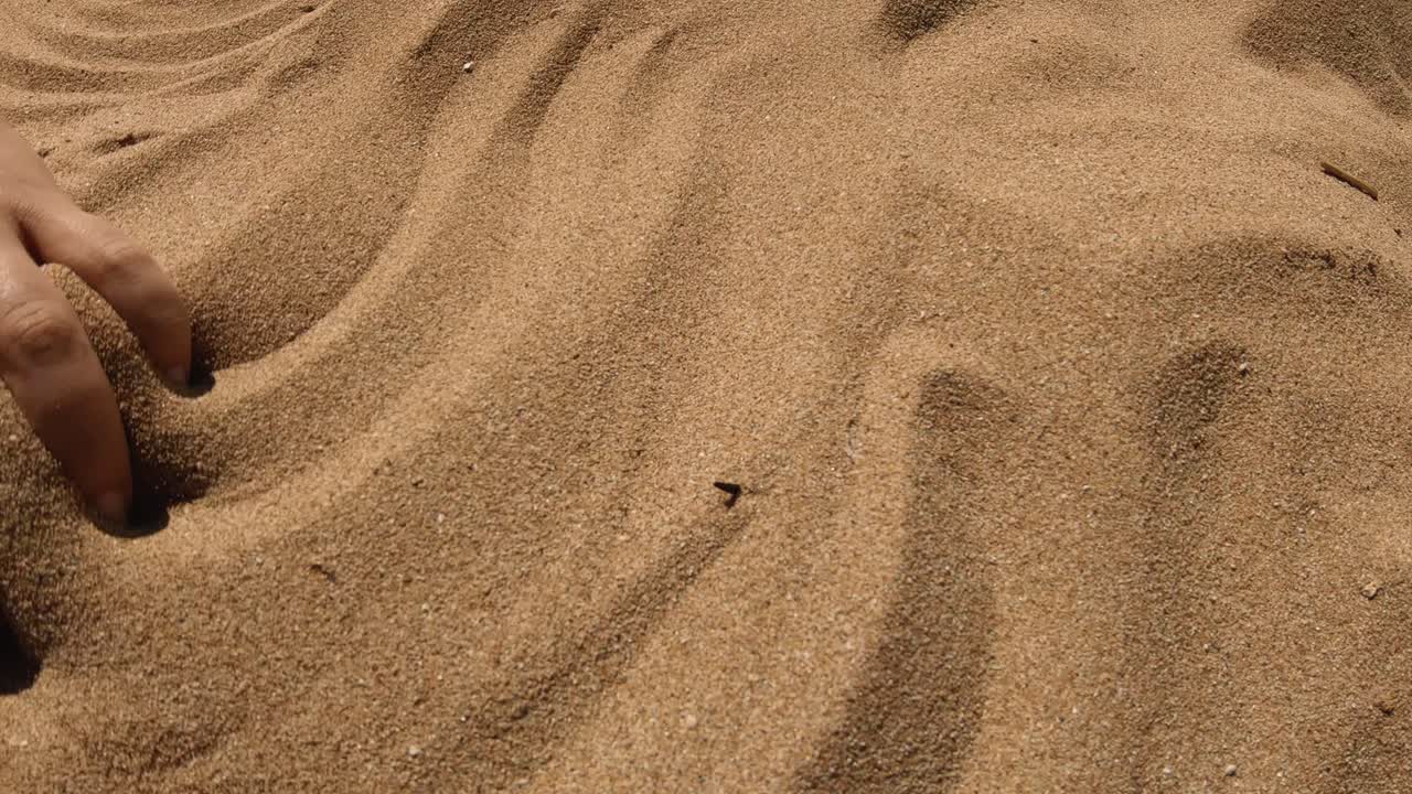 해변에서 모래 패턴을 만드는 손