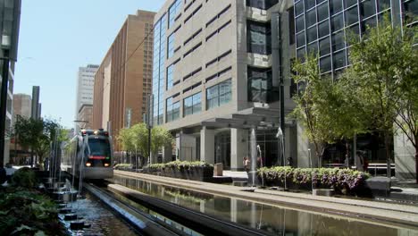 a rapid transit train moves quickly through downtown houston with fountains dancing 4