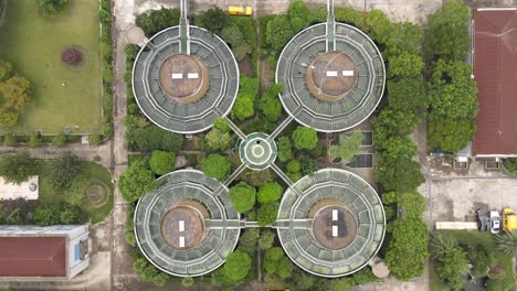 drone aerial view of sewage water treatment plant with storage tanks, trees