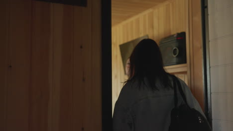 back view of three girls entering bar with dimly lit wooden interior as they look around, observing surroundings with television hanging on wall