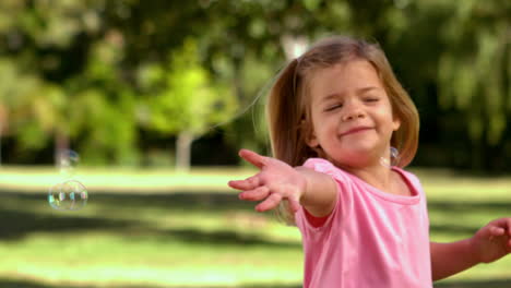 Kleines-Mädchen-Spielt-Mit-Seifenblasen-Im-Park