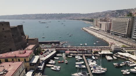 aerial view overlooking the marina porticciolo di santa lucia at the ovo castle, in naples, italy - circling, drone shot