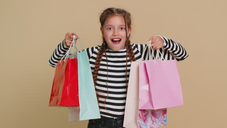 child girl kid showing shopping bags advertising discounts smiling amazed with low prices holidays