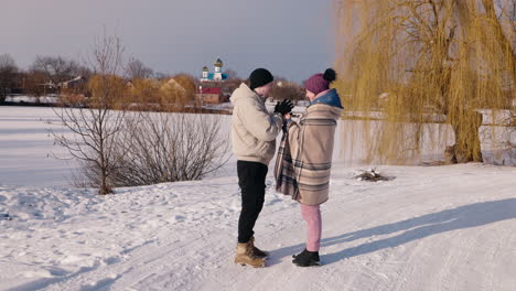 couple enjoying a winter day by a frozen lake