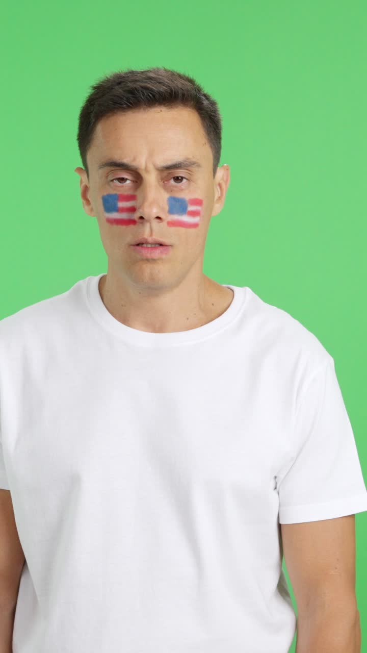 Man standing with USA flag painted on face smiling