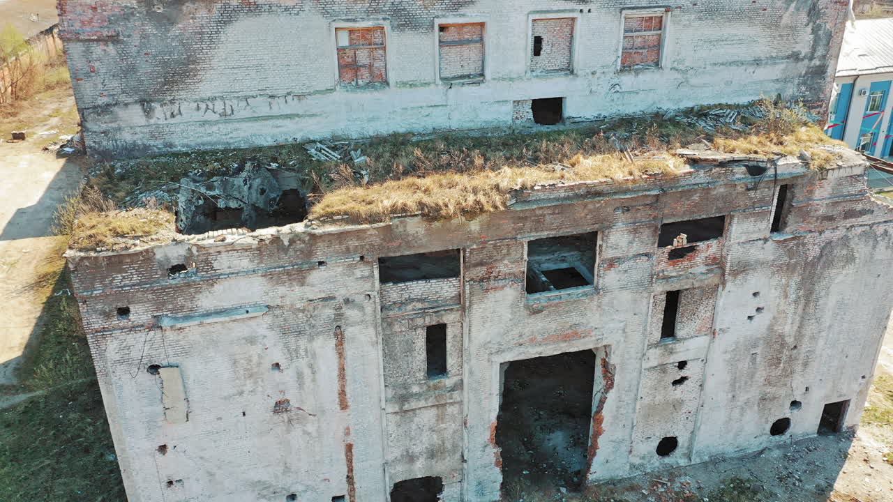 Front side of abandoned building exterior without doors and windows. Ruined plant after military actions. Aerial view.