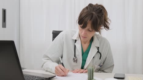 doctora profesional escribiendo prescripción médica en la mesa de la clínica
