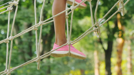 feet of an african american child walking along a cable stretched between trees