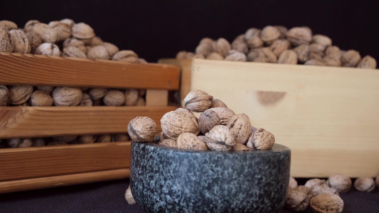 Scatole di noci su sfondo nero evidenziano i dettagli intricati dei loro gusci testurizzati, enfatizzando la loro bellezza naturale e i ricchi motivi organici.