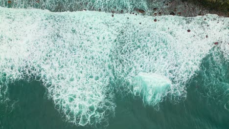 top-down-aufnahme von schäumigen meereswellen, die am strand in madeira, portugal, spritzen - drohnen-aufnahmen