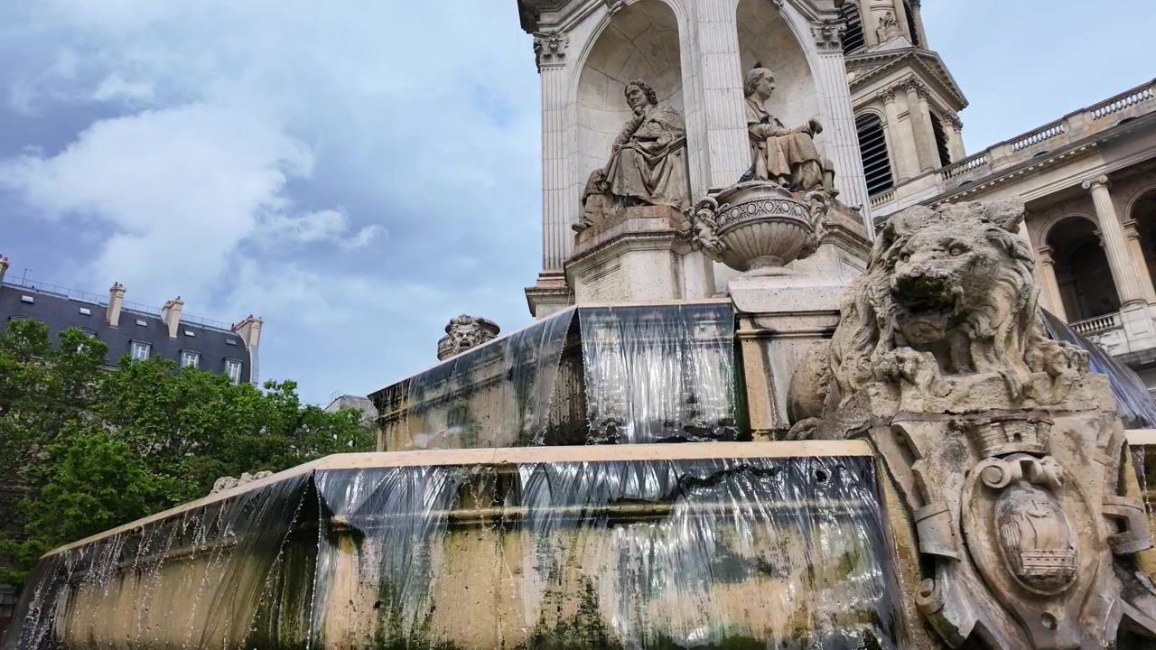 Toma de ángulo bajo de agua cayendo en cascada sobre niveles de piedra en un histórico monumento de fuente parisina.