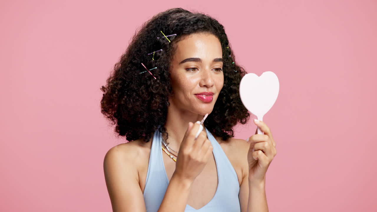 Woman applying lip gloss in a mirror