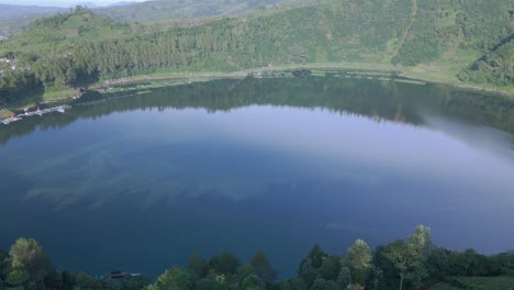 Aerial-view-of-Lake-with-calm-water-surrounded-by-green-tree-vegetation