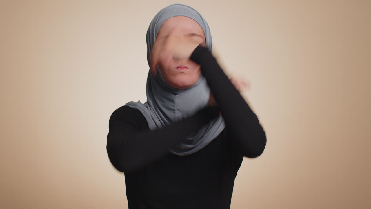 Upset woman in hijab showing thumbs down sign gesture, disapproval, dissatisfied dislike