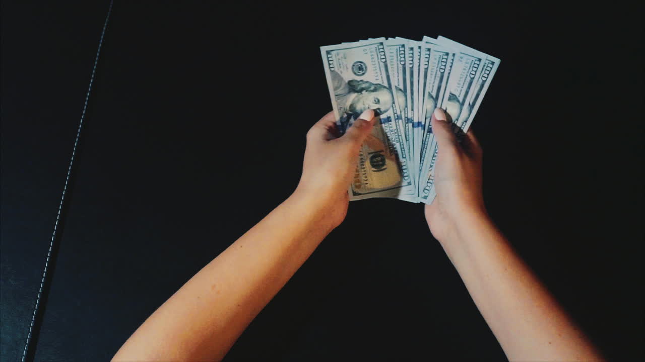 manos sosteniéndonos billetes de un dólar