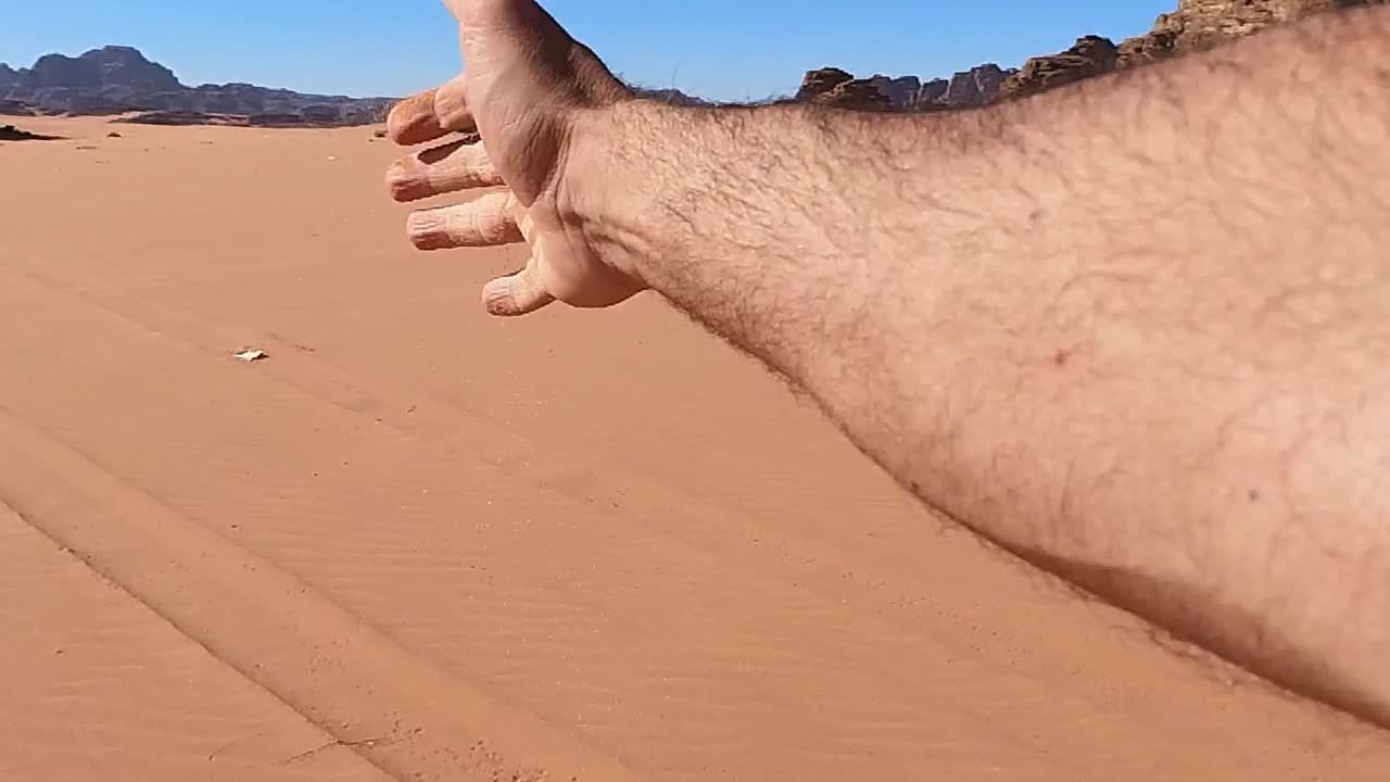 와디 럼 사막에서 모래를 흘리는 손