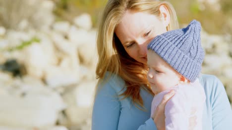 Vorderansicht-Einer-Kaukasischen-Mutter-Mittleren-Alters,-Die-An-Einem-Sonnigen-Tag-Ihr-Baby-Am-Strand-Anschaut-4k