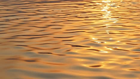 Hermoso-Primer-Plano-Cinematográfico-Del-Río-Sagrado-Ganges-Durante-El-Amanecer-Haciendo-Que-El-Agua-Brille-Todo-Dorado-Con-Las-Ondas