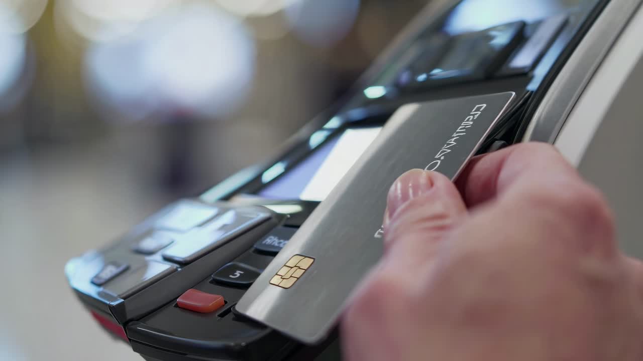 Close-up video shot of a hand inserting a credit card into a payment terminal