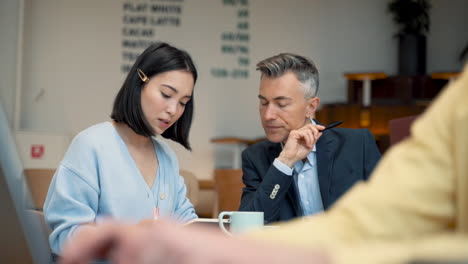 an young business woman check out her agenda with a businessman in a coffee shop