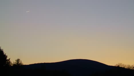 Flugzeug,-Das-Bei-Sonnenuntergang-In-Der-Ferne-über-Den-Berg-Fliegt