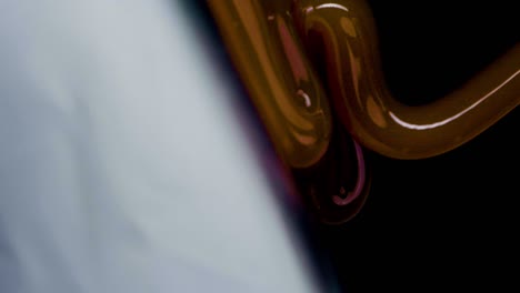 Slow-motion-vertical-shot-of-caramel-flowing-on-milk-cream-against-a-black-background