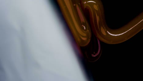 slow motion vertical shot of caramel flowing on milk cream against a black background