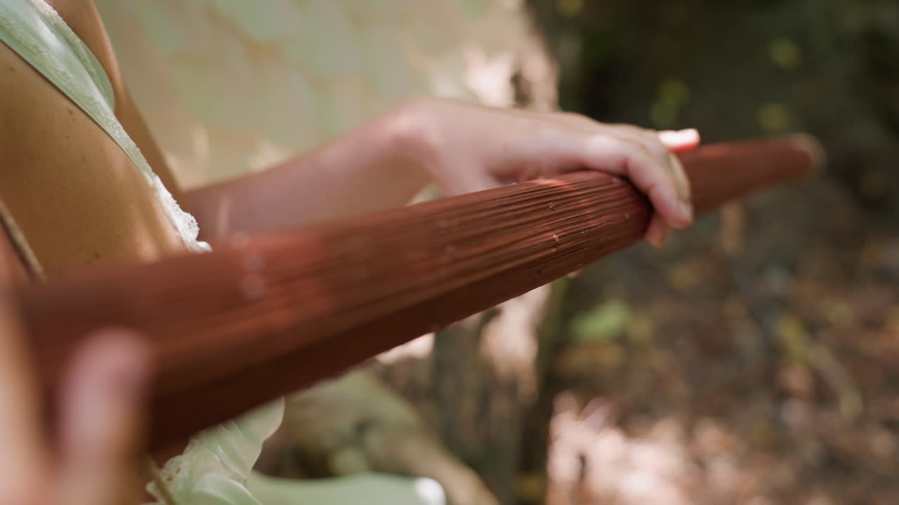 Close up of lady hand gently rotating wooden staff in soft blur forest sunlight, focus on natural texture and graceful motion, symbolizing calm energy, mindfulness, and quiet connection with nature