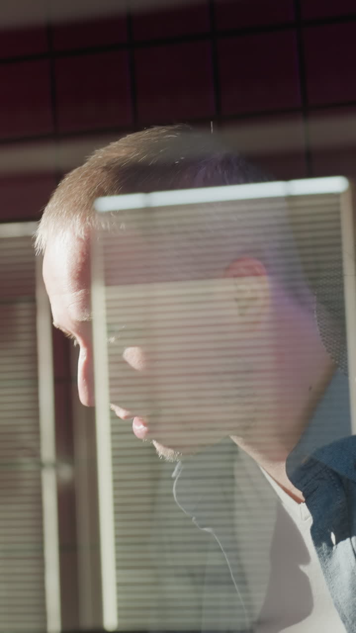 un hombre con una camisa negra ayuda a otro con una camiseta azul de manga larga colocándole auriculares en un estudio a prueba de sonido rojo, preparándose para una sesión de grabación con un profesional, colaborativo