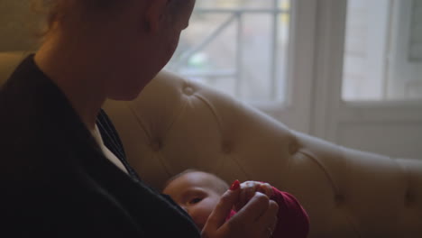 mother breast-feeds her daughter near window