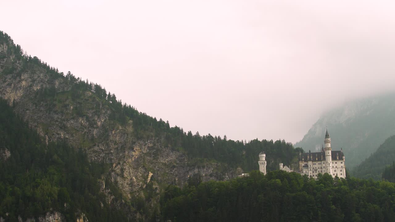 muñeca aérea en el espectacular castillo de neuschwanstein en una ladera rodeada por un denso bosque de pinos verdes en un día nublado, baviera, alemania